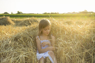 Kleines Mädchen sitzt auf dem Stroh eines havarierten Feldes - LVF07357
