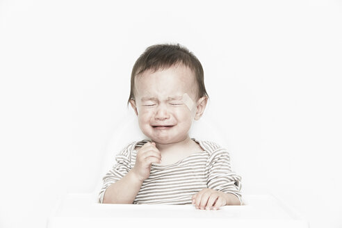 Kleiner Junge mit Pflaster im Gesicht, weinend - ISF19120