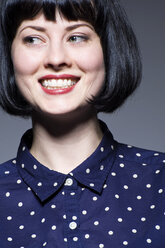 Junge Frau in blau gepunkteter Bluse schaut weg, lächelt - ISF19144