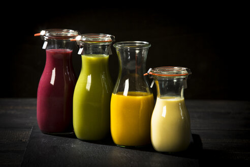 Vier Glasflaschen mit verschiedenen Smoothies - MAEF12680