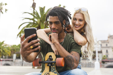 Porträt eines jungen multikulturellen Paares, das ein Selfie mit seinem Smartphone macht - WPEF00716