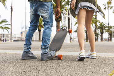 Spanien, Barcelona, Beine eines multikulturellen jungen Paares mit Longboard auf der Promenade - WPEF00722