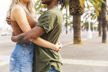 Spain, Barcelona, multicultural young couple embracing on promenade, partial view - WPEF00726