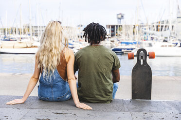 Spanien, Barcelona, Rückenansicht eines multikulturellen jungen Paares mit Longboard im Yachthafen - WPEF00727