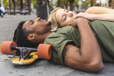 Multicultural young couple with longboard relaxing together - WPEF00732