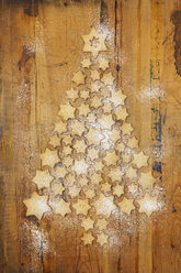 Star-shaped biscuits forming Christmas Tree on wooden background - GWF05617