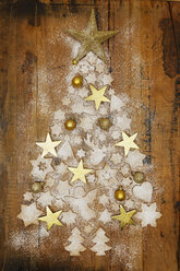 Christmas cookies and golden Christmas baubles and stars forming Christmas Tree on wood - GWF05620