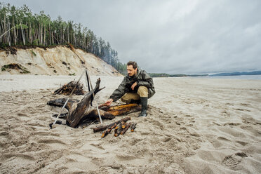 Mann sammelt Brennholz am Strand und bereitet ein Lagerfeuer vor - VPIF00410