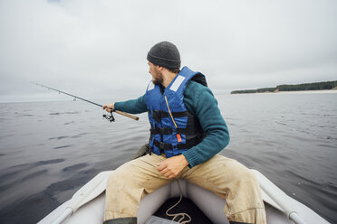 Mann sitzt auf einem Boot und fischt mit einer Angelrute - VPIF00428