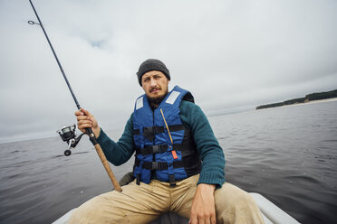 Man sitting on boat fishing with fishing rod - VPIF00429