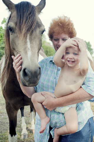 Großmutter und Kleinkind mit Pony, lizenzfreies Stockfoto