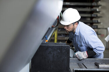 Arbeiter an einer Maschine in einer Metallfabrik - ISF19216