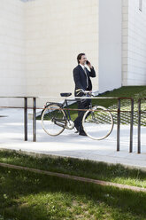 Mittlerer erwachsener Geschäftsmann mit Fahrrad und Mobiltelefon - ISF19273