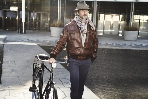 Mittlerer erwachsener Mann mit Fahrrad in der Stadt - ISF19276