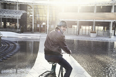 Mid adult man enjoying bike ride in city - ISF19277