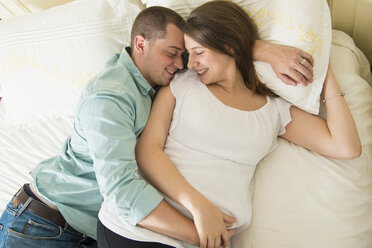 Schwangere Frau und Partner auf dem Bett liegend - ISF19299