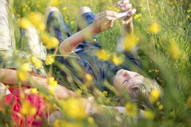 Boys lying in long grass playing on smartphone - ISF19308