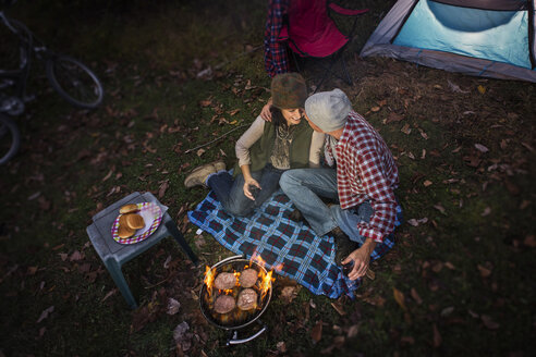 Mature couple sitting outside tent with barbecue and glass of wine - ISF19555