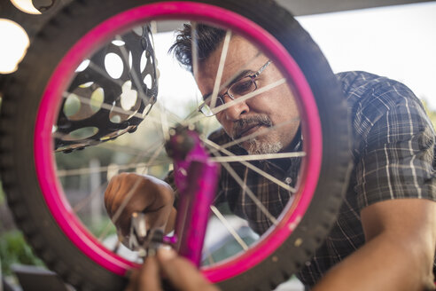 Mann repariert Rad eines Kinderfahrrads - ZEF15908