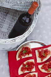 Bruschetta und eine Flasche Wein auf einer Picknick-Decke - MAUF01618