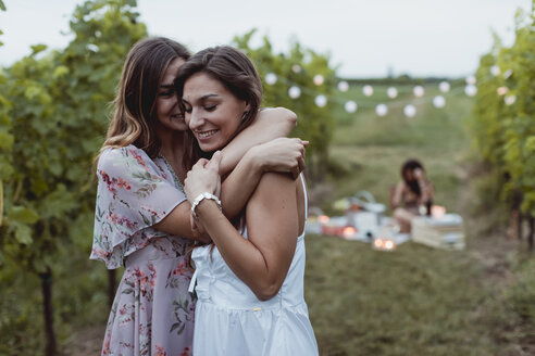 Zwillingsschwestern umarmen sich beim Sommerpicknick in einem Weinberg - MAUF01643