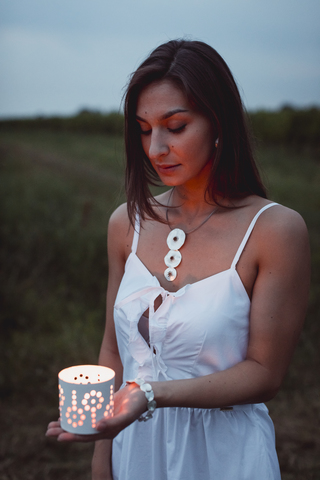 Young woman in nature, holding candle in the evening stock photo