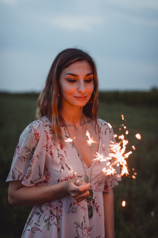 Young woman in nature, burning sparkler in the evening stock photo