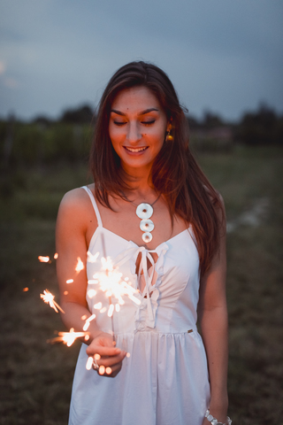 Junge Frau in der Natur, brennende Wunderkerze am Abend, lizenzfreies Stockfoto