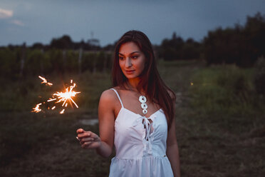 Junge Frau in der Natur, brennende Wunderkerze am Abend - MAUF01658