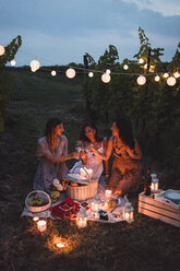 Friends having a picnic in a vineyard on summer night - MAUF01662
