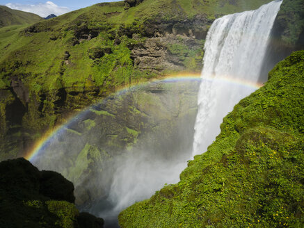 Der Wasserfall Skogafoss, eine Kaskade über eine steile Klippe und ein Regenbogen im Nebel. - MINF03090