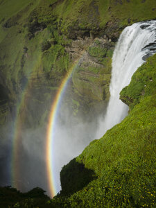 Der Wasserfall Skogafoss mit einem doppelten Regenbogen im Nebel und dem aus dem Wasser aufsteigenden Wasserdampf. - MINF03092