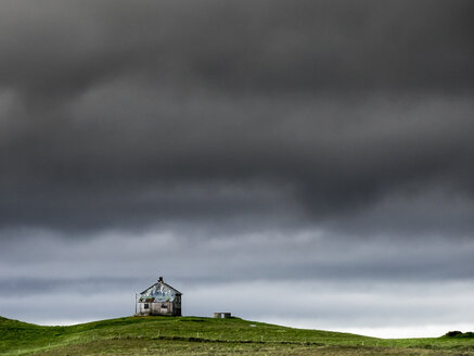 Eine Scheune auf dem Kamm eines Hügels und dunkle Gewitterwolken, die über dem Land schweben. - MINF03104