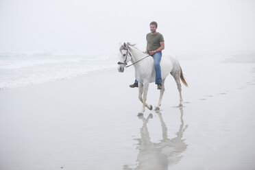Mann reitet Pferd am Strand - ISF19581