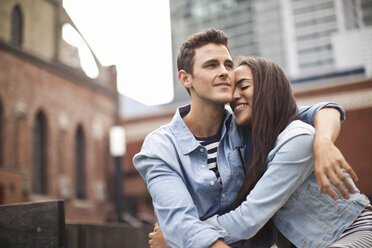 Young couple embracing in city, smiling - ISF19601