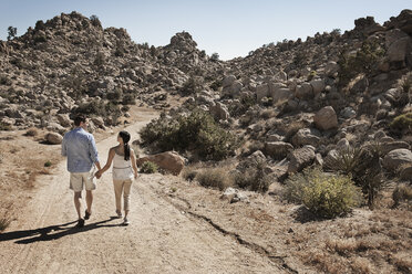 Two people, a couple walking through a rocky landscape along a path. - MINF03125