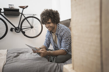 Loft living. A bicycle hanging on a wall. A man using a digital tablet. - MINF03142