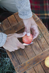 A man cutting up an apple with a sharp knife. - MINF03203