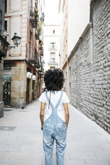 Spain, Barcelona, back view of woman with curly hair wearing dungarees - JRFF01729