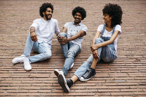 Three friends sitting on a square having fun together - JRFF01735