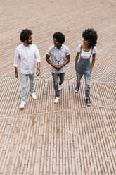 Drei Freunde gehen auf einem Platz spazieren und haben Spaß zusammen - JRFF01738