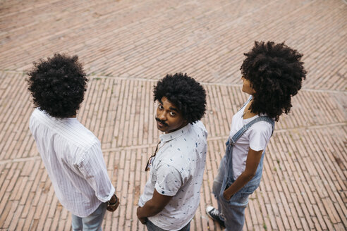 Three friends with curly hair standing on a square - JRFF01741