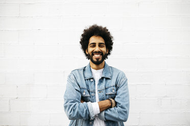 Portrait of grinning young man in front of white wall - JRFF01755