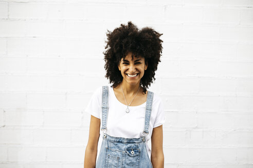 Portrait of laughing woman in front of white wall - JRFF01758