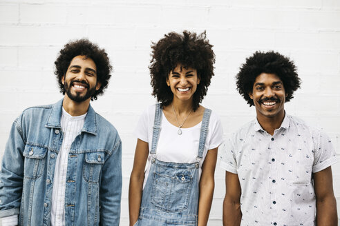 Group picture of three laughing friends in front of white wall - JRFF01759