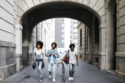 Spain, Barcelona, three friends with racing cycle walking on the street - JRFF01762