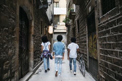 Spain, Barcelona, back view of three friends walking down an alley - JRFF01769