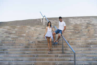 Junges Paar geht eine Treppe hinunter, Mann rutscht auf dem Geländer - AFVF01188