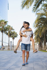 Happy couple in the city, man carrying his girlfriend piggyback - AFVF01193