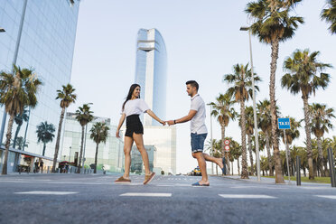 Young couple crossing street in the city, holding hands - AFVF01206